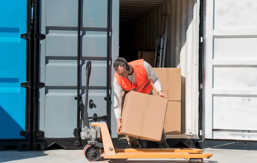 Pracownik ładuje kontener morski. Wykorzystanie kontenera na magazynowanie towarów w kartonach.