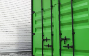 Zbliżenie na jaskrawozielony, stalowy kontener morski. Jego trwała, kofalowa konstrukcja jest idealnym przykładem na nowe i używane kontenery morskie, jakie można znaleźć w naszej ofercie. Widać solidne wrota z czarnymi prętami i mechanizmami ryglowania, typowe dla kontenera magazynowego przeznaczonego do bezpiecznego transportu towarów.